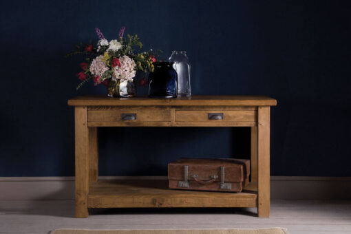 Rustic plank consoe table , with a bunch of flowers placed on top.